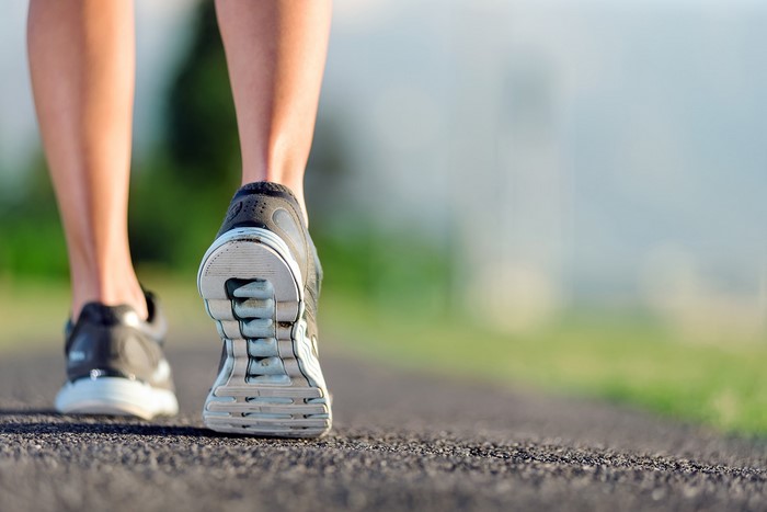 Close-up of person's legs and athletic shoes walking on pavement