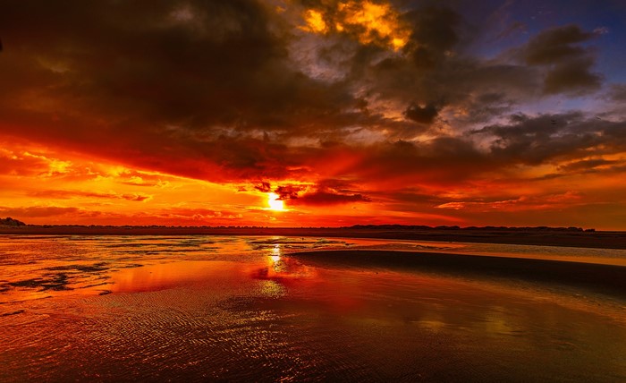 Dramatic sunset over a wet beach with reflections