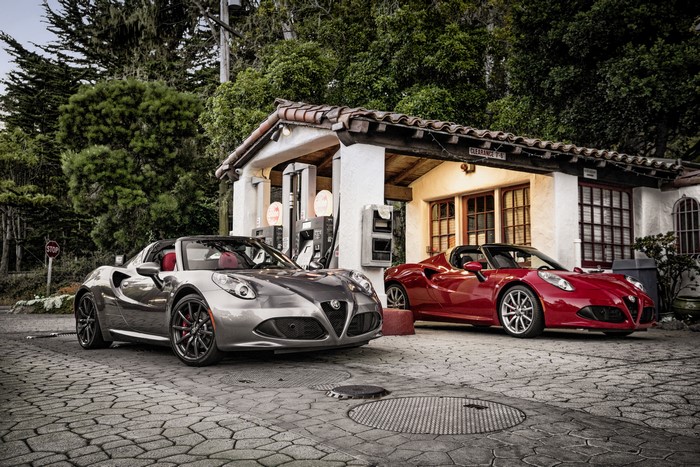 Two Alfa Romeo 4C Spider cars at a vintage gas station