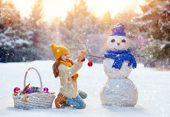 Girl Decorating a Snowman with Christmas Ornaments
