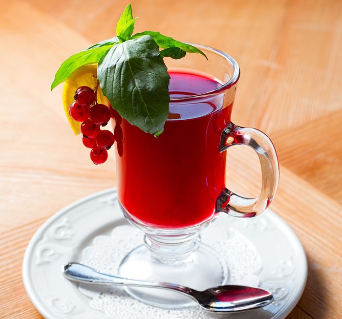 Red currant drink with mint and lemon on a plate with spoon