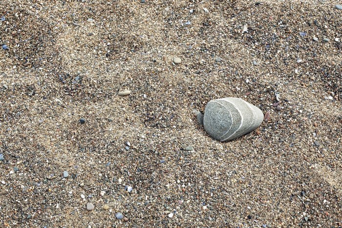 Closeup of a striped stone on a sandy beach