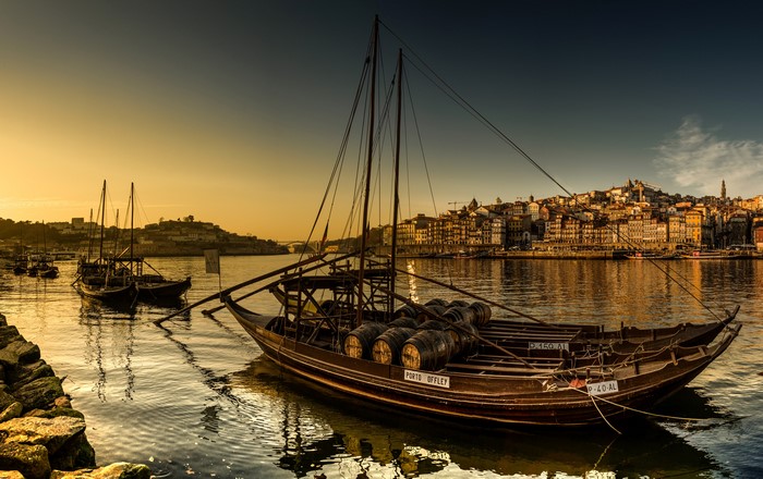 Boats with barrels on the Douro River in Porto, Portugal at sunset