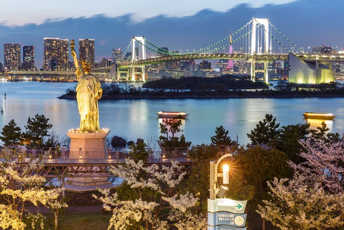 Statue of Liberty replica and Rainbow Bridge at dusk in Tokyo, Japan