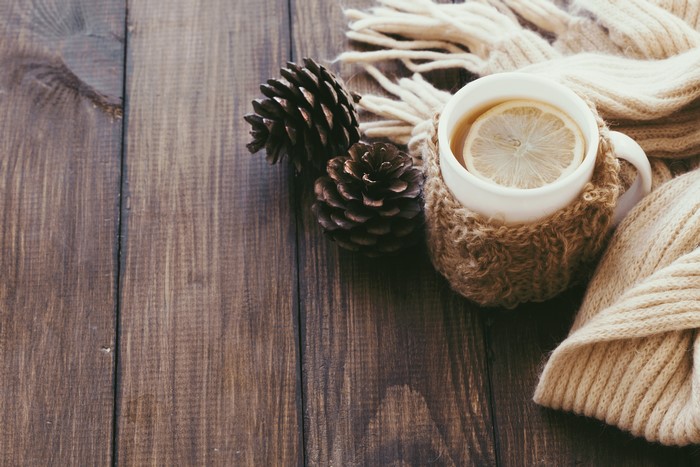 Cup of tea with lemon and pine cones on wood
