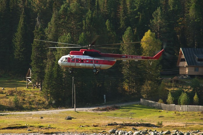 Mi-8 helicopter flying over a forest with a cabin