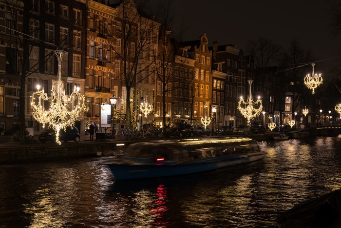 Amsterdam canal at night with boat and fairy lights