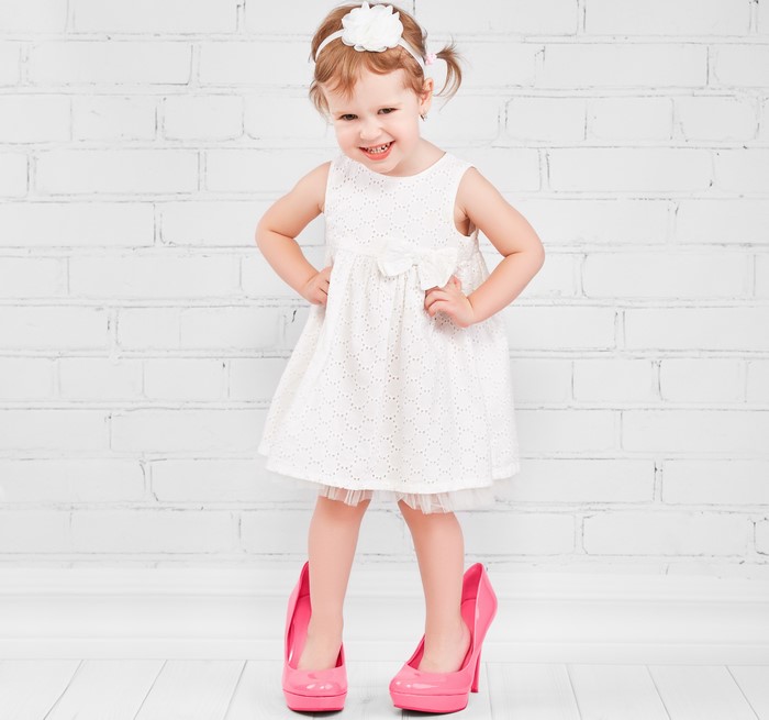 Little girl in white dress wearing pink high heels
