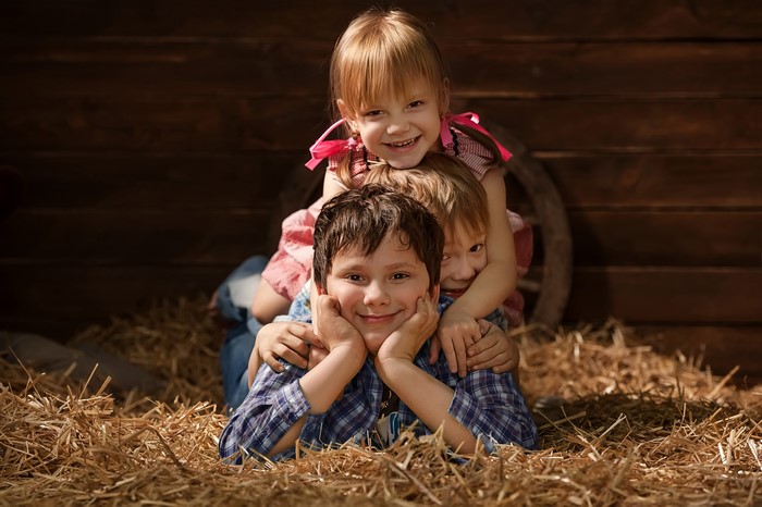 Three Children Stacked in Hay
