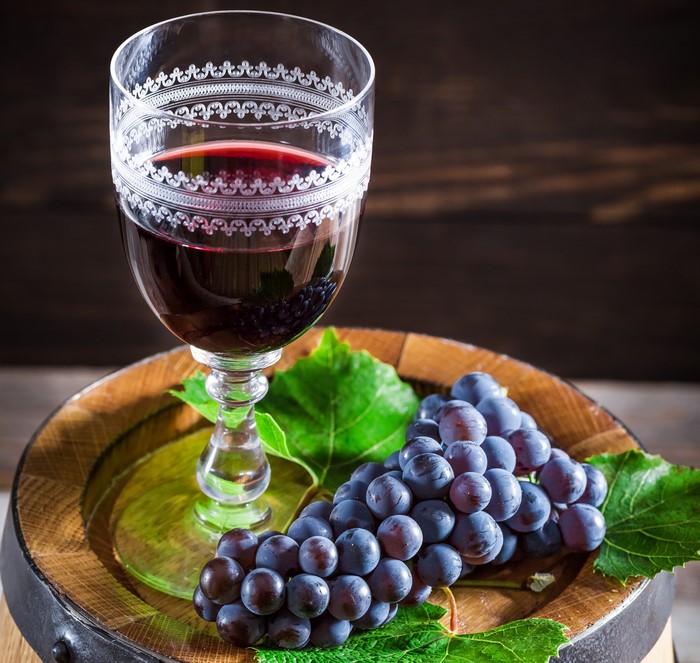 Glass of red wine and grapes on a barrel