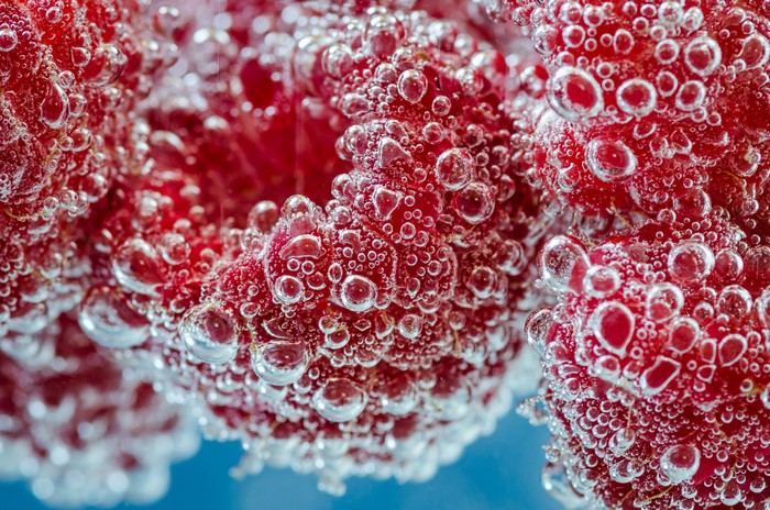 Raspberries submerged in sparkling water with bubbles