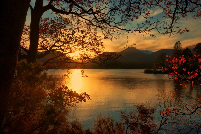 Sunset over a lake with mountains and trees in Keswick, England