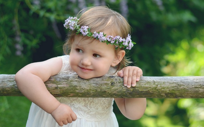 Baby girl with flower crown on wooden fence