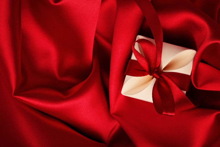 Red satin fabric with a gift box and red ribbon