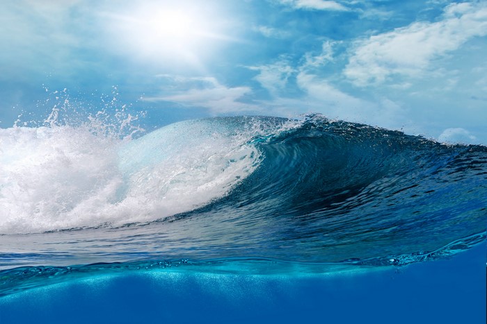 Ocean wave crashing under a sunny sky