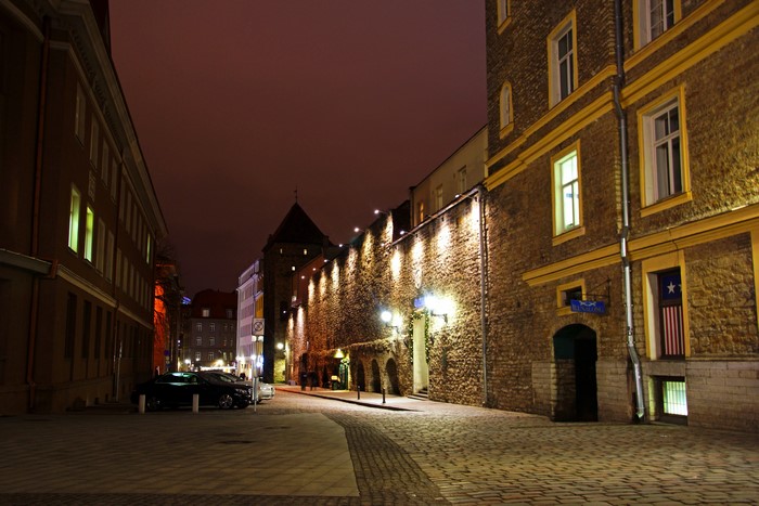 Tallinn street at night with stone walls and buildings