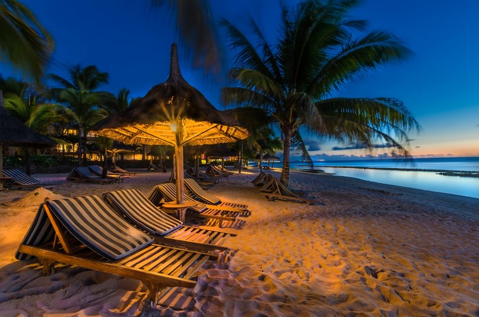 Beach loungers and palm trees at dusk in Mauritius