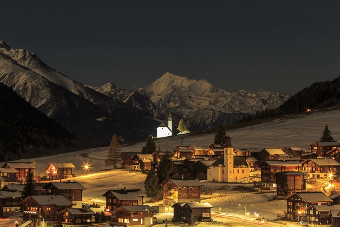 Alpine village in Switzerland at night with snow-covered mountains