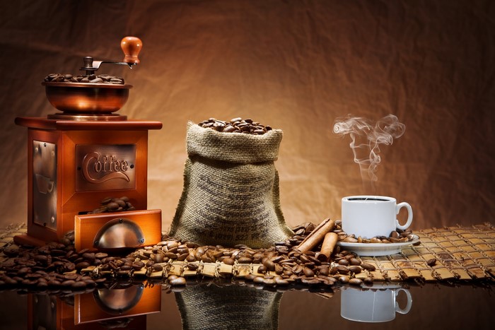 Coffee beans, grinder, and cup with steam