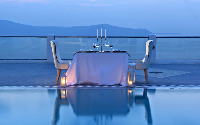 Romantic dinner table setting by the pool at dusk