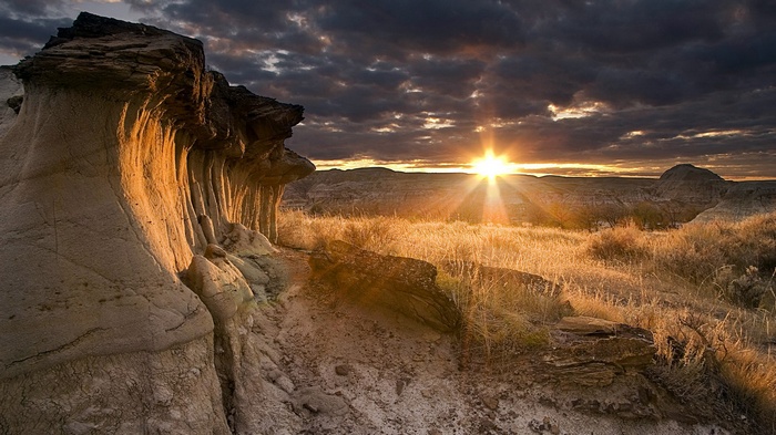 Sunset over Badlands rock formations and dry grass