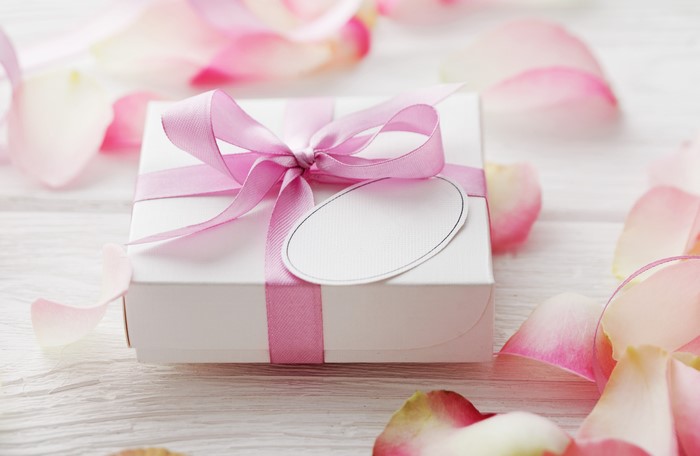 Gift box with pink ribbon and rose petals