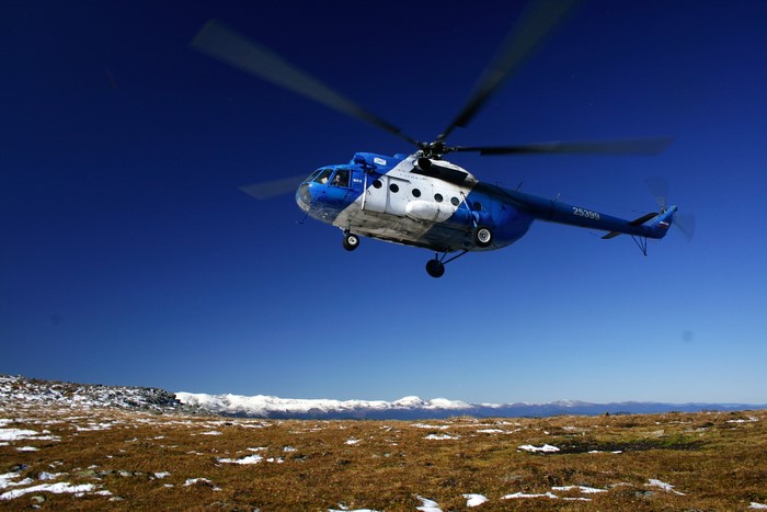 Blue and white Mi-8 helicopter flying over mountains