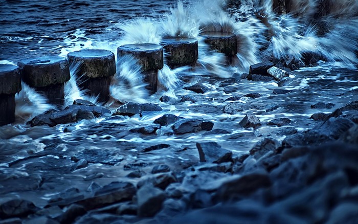 Waves crashing on wooden posts and rocks