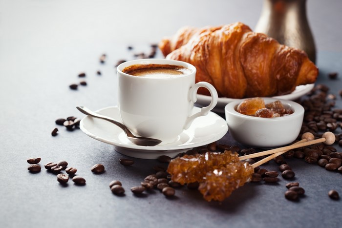 Coffee cup with croissant and coffee beans