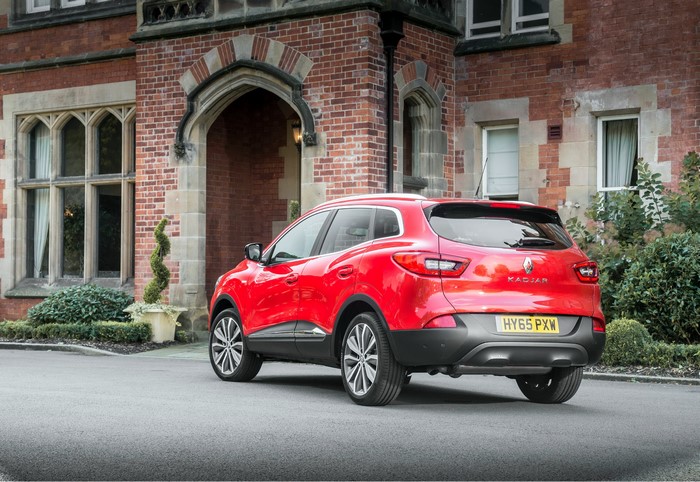 Red Renault Kadjar dCi 130 parked in front of a brick building