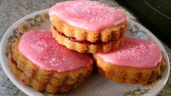 Three jam-filled iced cookies with sprinkles