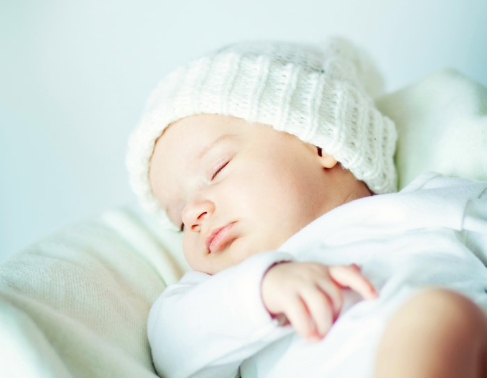 Baby sleeping wearing a white winter hat