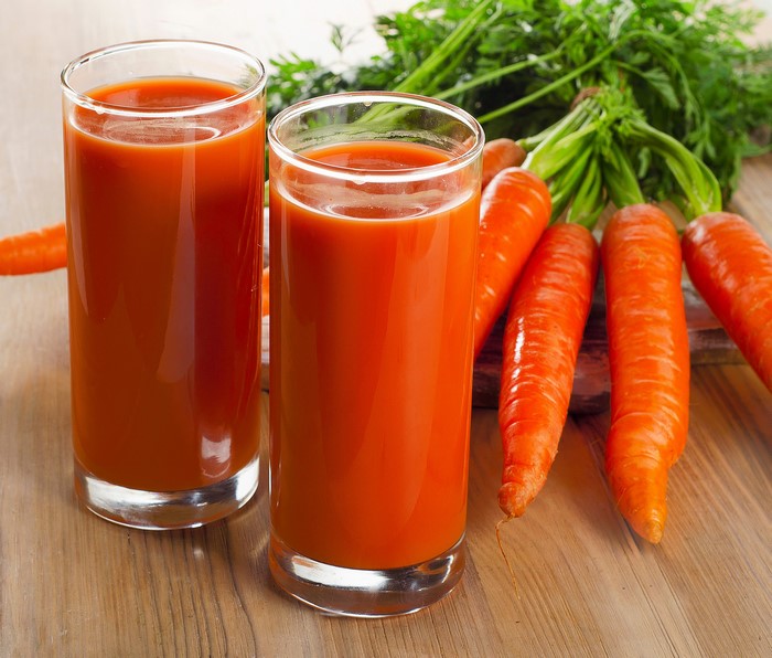 Two glasses of carrot juice with fresh carrots