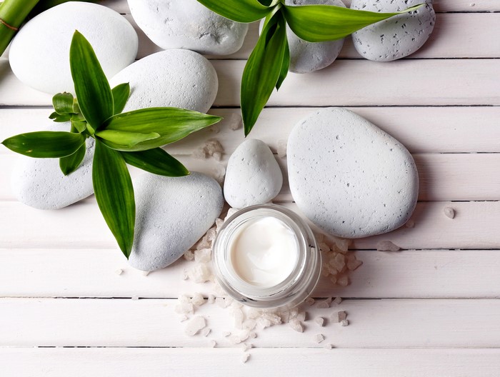 Spa stones, bamboo leaves, and cream on wood planks
