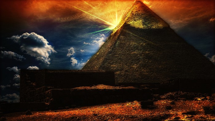 Pyramid with sun rays over ancient ruins
