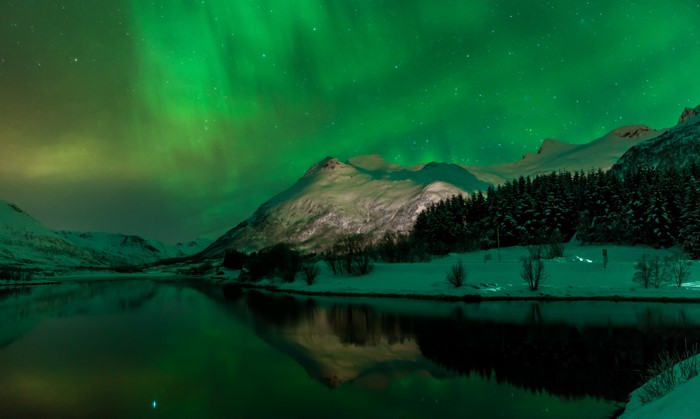 Aurora Borealis over snowy mountains and lake in Svolvaer, Norway