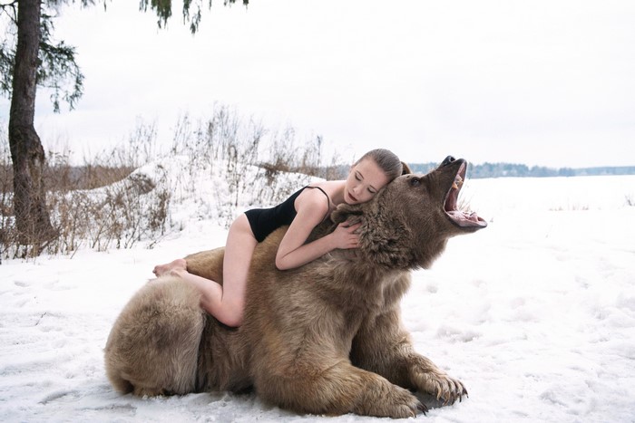 Girl hugging a brown bear in the snow