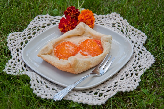 Apricot pastry on a plate with flowers and fork