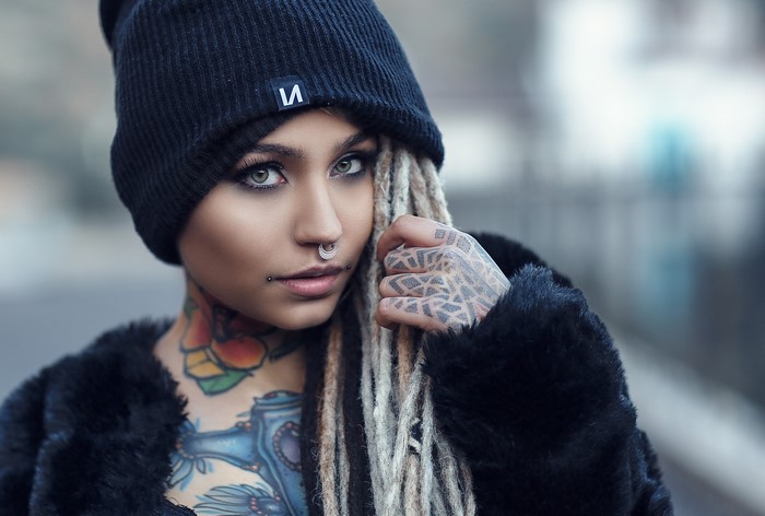 Woman with dreadlocks and tattoos wearing a winter hat