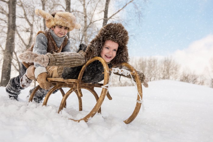 Two boys sledding in the snow