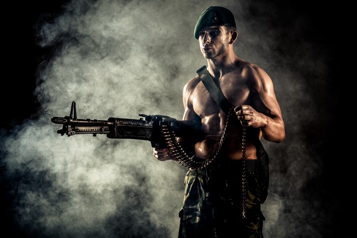 Man in green beret holding a machine gun