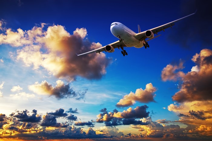 Airplane flying through clouds at sunset
