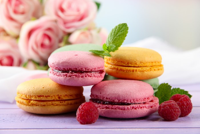 Pink, yellow, and green macarons with raspberries and roses