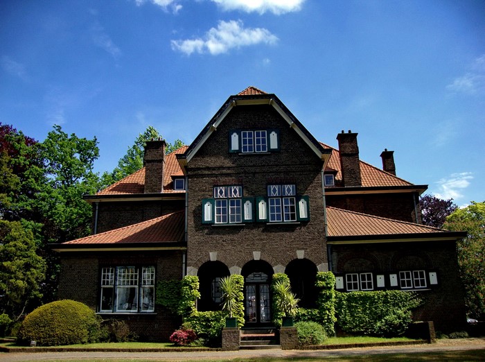 Brick mansion with arched entrance and trees