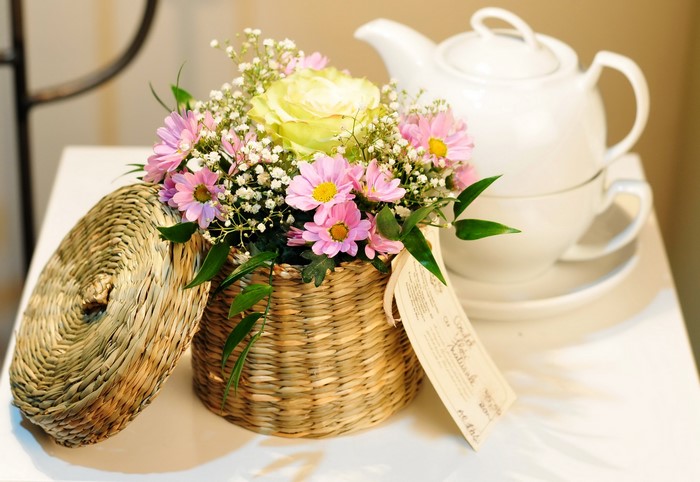 Flower arrangement in a wicker basket with a teapot