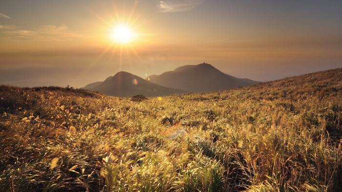 Golden sunset over grassy mountains