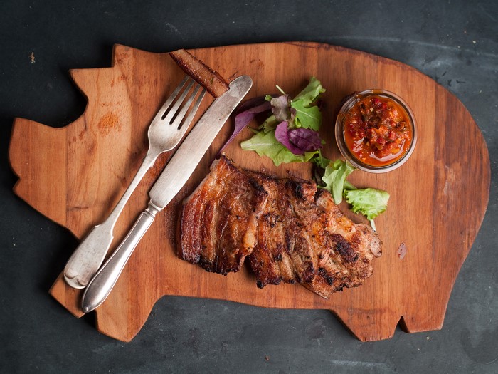Grilled ribs with sauce and salad on a wooden board