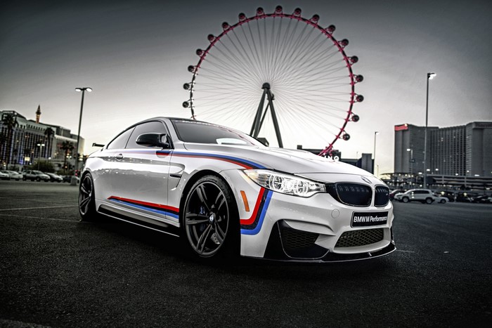 White BMW M4 Coupe with BMW M Performance decals and Ferris wheel