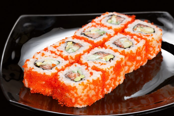 Sushi with salmon and avocado on a black plate