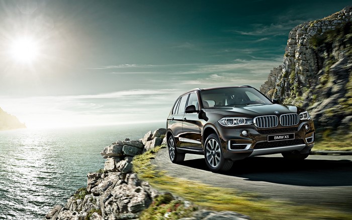 Brown BMW X5 driving on a coastal road